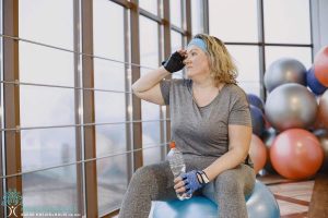 A woman sitting on an exercise ball in a gym.