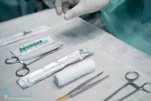 A person is holding a pair of scissors in an operating room.