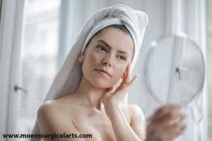 A woman in a towel looking at herself in the mirror.